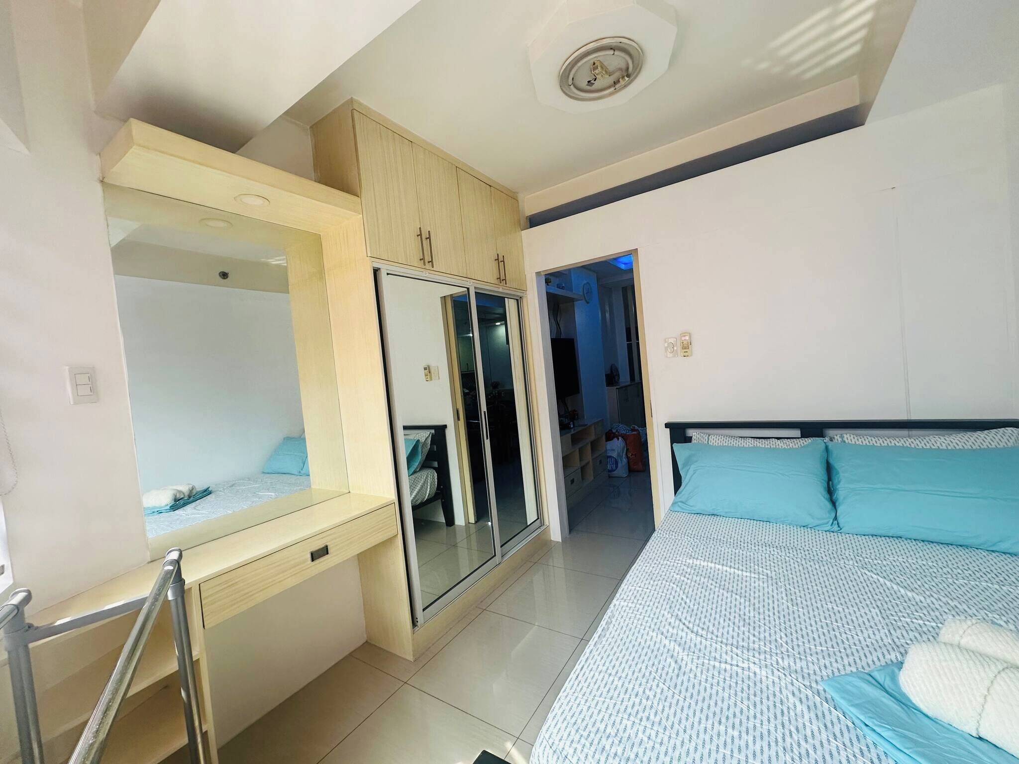A bedroom with a bed, a wardrobe, a mirror, and a door leading to another room.