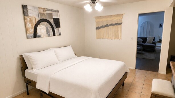 Ein Schlafzimmer mit einem Bett, einem Sessel und Kunstwerken an den Wänden.