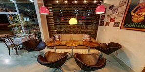 Ein modernes Interieur mit einer Sitzecke, die runde Tische und Ledersessel sowie eine Wand aus Holzlatten und Pendelleuchten umfasst.