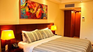 Habitación de hotel con una cama grande, dos lámparas de noche, un teléfono y un cuadro en la pared.
