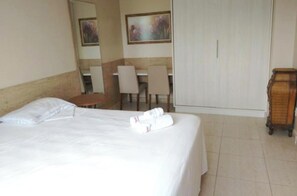 Ein Hotelzimmer mit Bett, einem Sessel, einem Schreibtisch und einem Kleiderschrank.