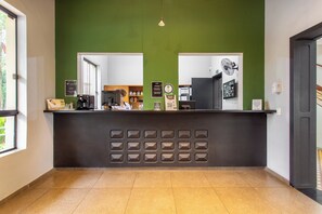 Ein Empfangstresen mit grüner Wand, einer Kaffeemaschine und einem Spiegel.