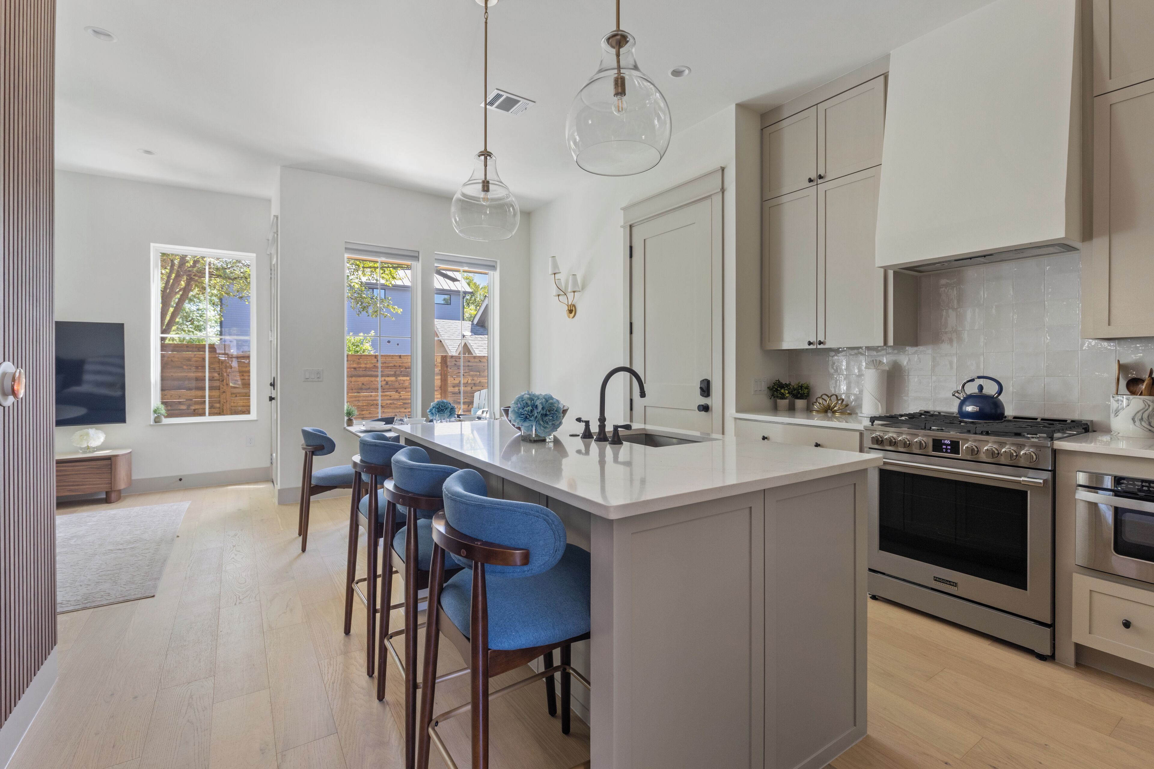 A modern kitchen with a large island, stainless steel appliances, and a view to the outside.