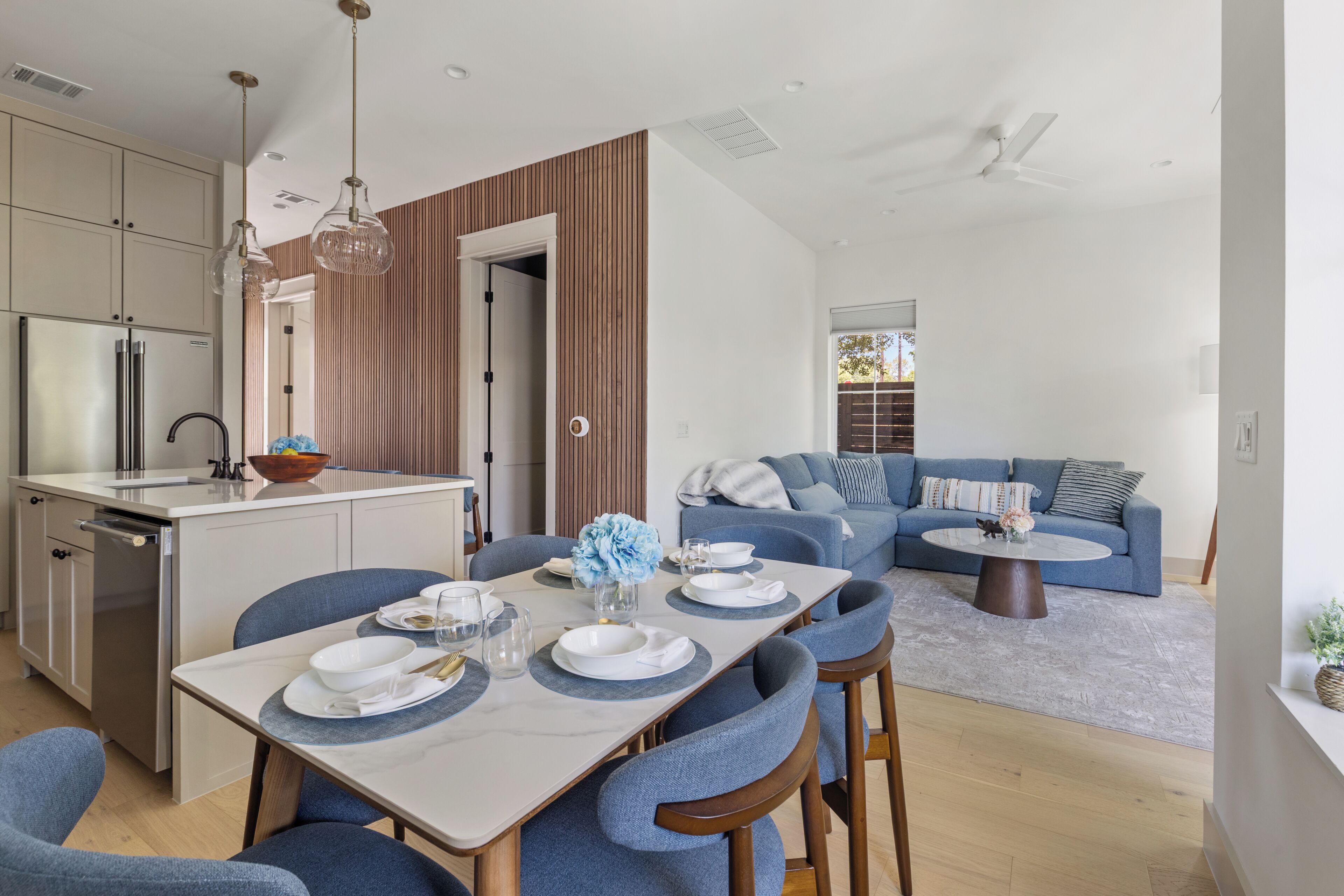 A modern kitchen with a dining area, a built-in oven, and a large window.