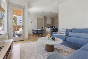 Ein modernes Wohnzimmer mit einem blauen Sofa, einem runden Couchtisch und einem Essbereich mit blauen Stühlen.