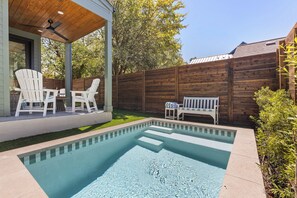 Ein Garten mit Swimmingpool, zwei Adirondack-Stühlen, einer Bank und einem Holzzaun.