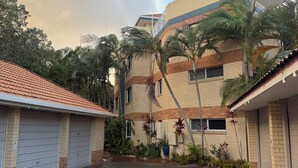 Un edificio de varios pisos con fachada de ladrillo, estacionamiento cubierto y zonas verdes circundantes.