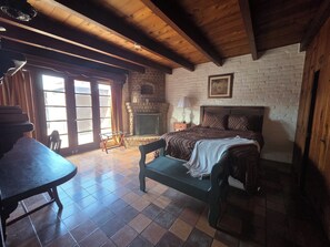 A room with a bed, a bench, a fireplace, and a table. - Unique 2-bedroom Castle house near U of A (Tucson)