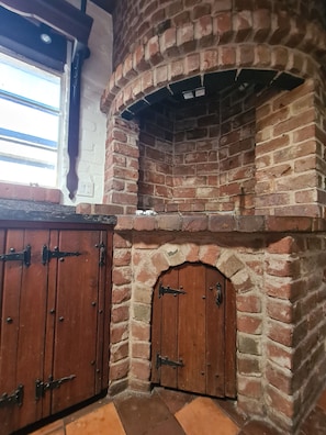 Ein Kamin aus Ziegelsteinen mit einer Holztür und einem Fenster darüber.