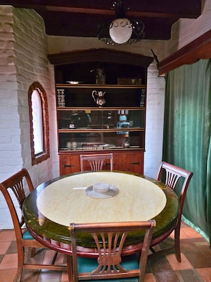 Un coin repas comprenant une table ronde, des chaises, un buffet avec des portes en verre et un luminaire suspendu.