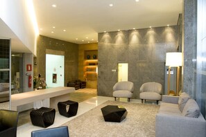 Eine moderne Lobby mit einer Rezeption, einer Sitzecke und einem Kamin.
