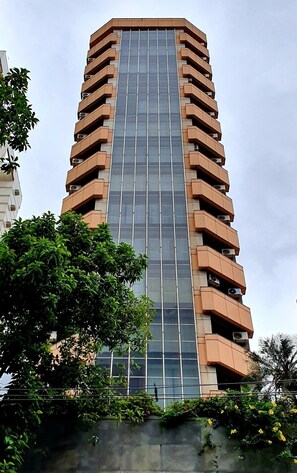 Ein hohes Gebäude mit moderner Architektur, das eine zentrale Glasfassade und mehrere Balkone aufweist.