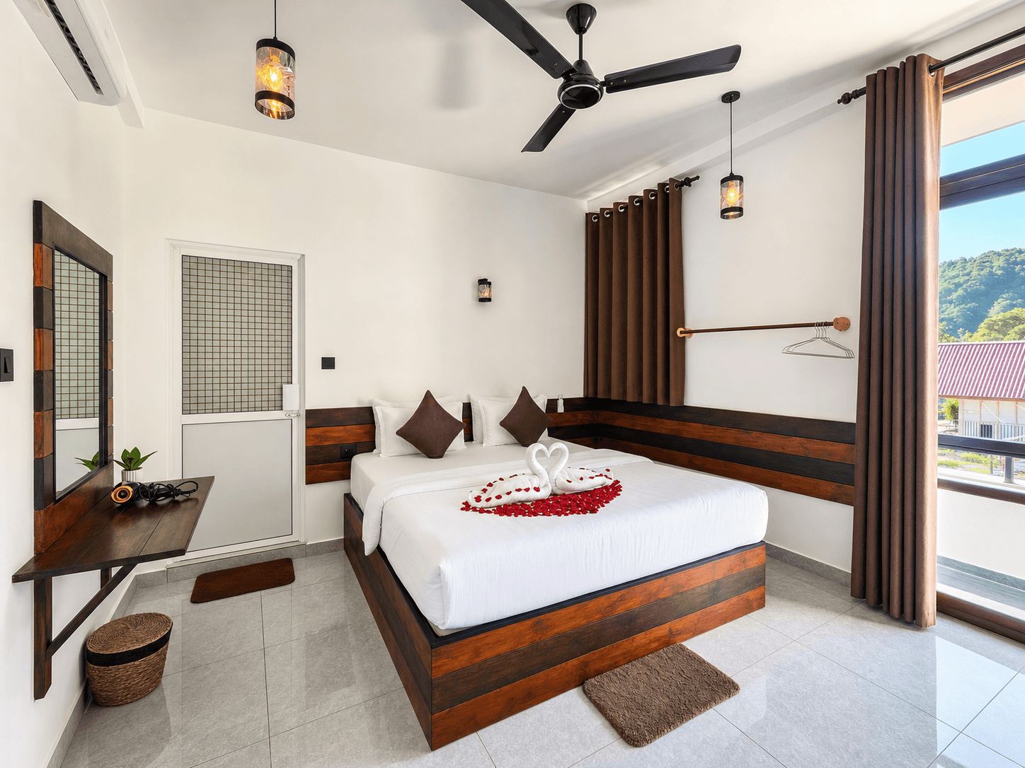 Ein Hotelzimmer mit Bett, Schreibtisch, Deckenventilator und Blick ins Freie.