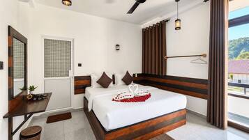 Ein Hotelzimmer mit Bett, Schreibtisch, Deckenventilator und Blick ins Freie.