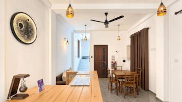 A modern kitchen with a wooden countertop, pendant lights, and a ceiling fan.