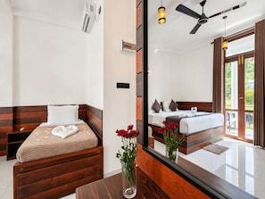 Une chambre d’hôtel avec un lit en bois, un grand miroir, un ventilateur de plafond et une vue sur l’extérieur.