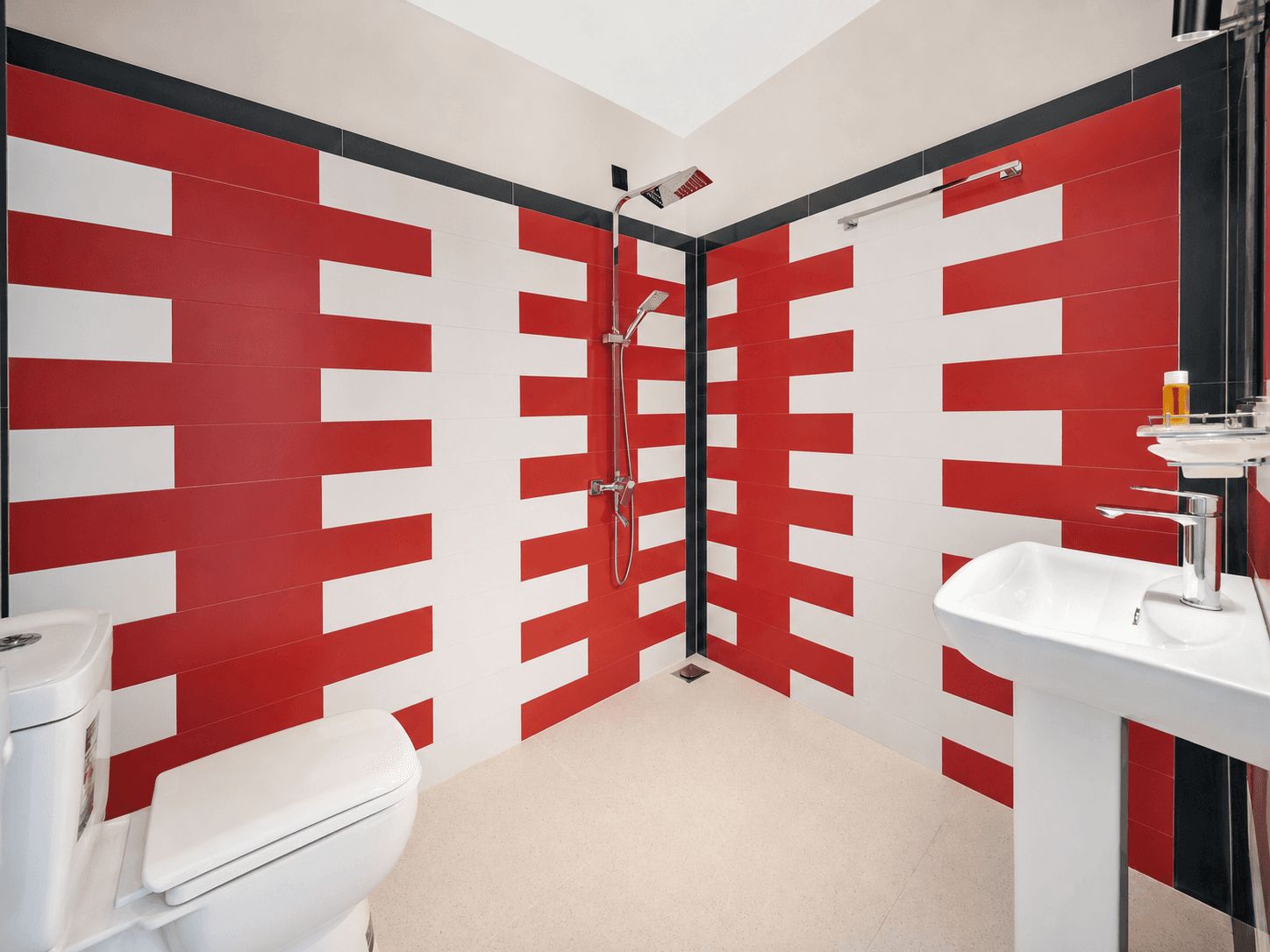 A modern bathroom with a red and white striped wall design, a white toilet, a sink, and a shower.