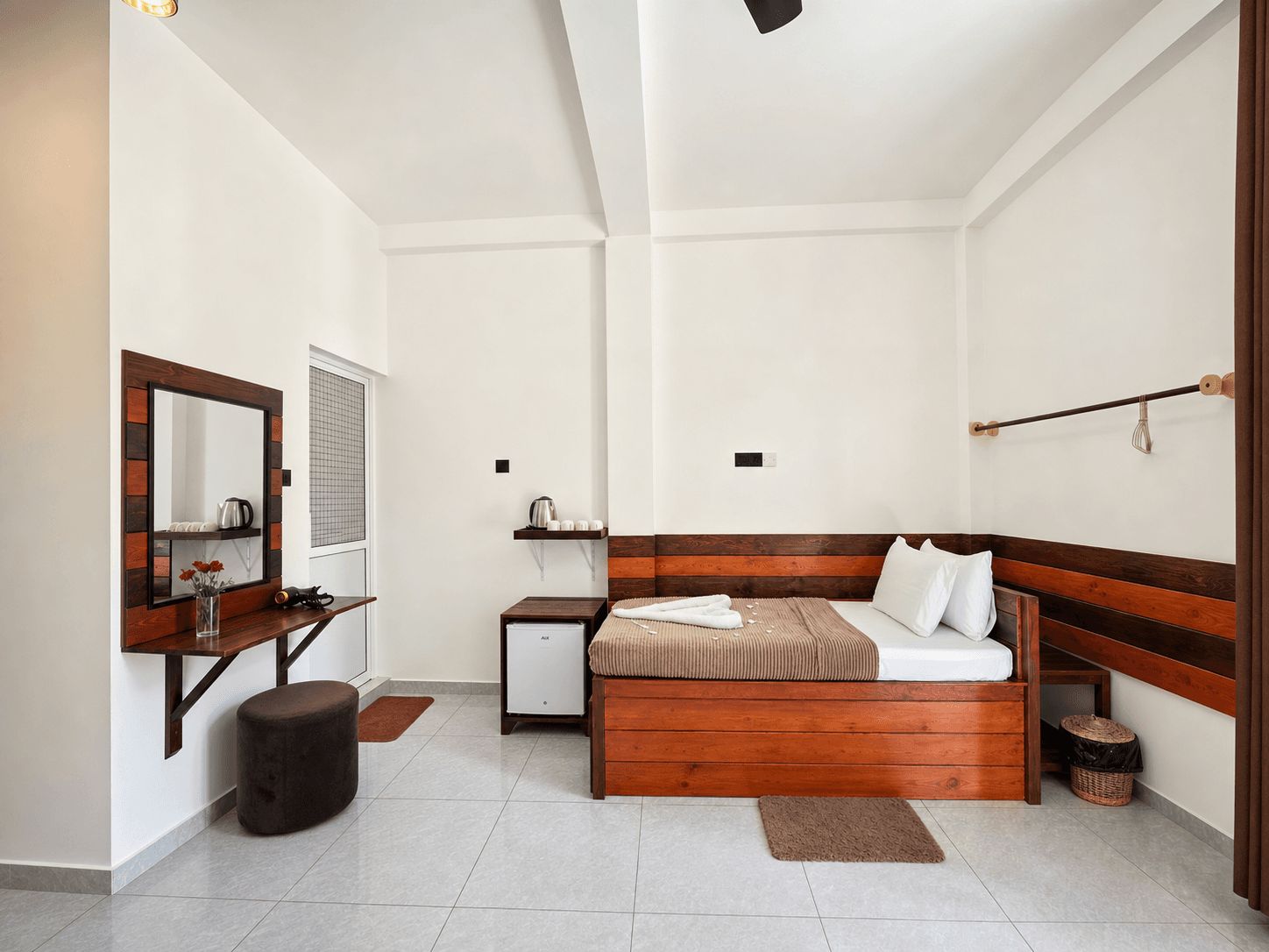 Une chambre moderne avec une tête de lit en bois, une table de chevet, un petit meuble de chevet, un miroir et une fenêtre avec des stores.