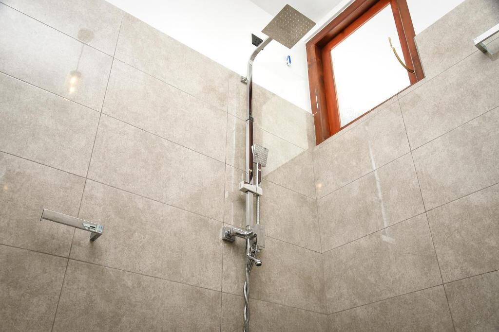 Ducha con cabezal de ducha de mano y llave instalada en la pared.