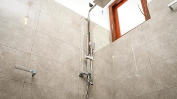 Ducha con cabezal de ducha de mano y llave instalada en la pared.