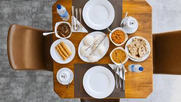 A dining table with a variety of dishes, including rice, flatbreads, and a bowl of curry, set for four people.