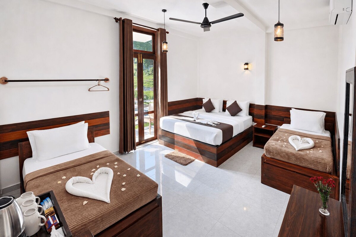 A hotel room with a bed, a desk, a chair, a coffee maker, and a window with curtains.