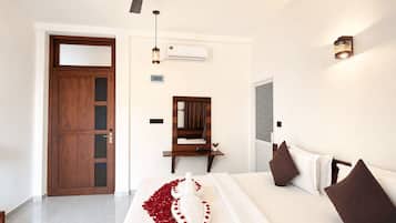 A hotel room with a bed, a desk, a mirror, a ceiling fan, and an air conditioning unit.