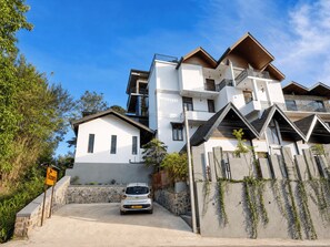 A modern multi-story residential building with a car parked in the driveway.