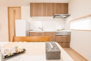 A compact kitchenette with wooden cabinets, a stainless steel range hood, and a small countertop. - SERENE | Nishikujo, 5th Floor | 100 ㎡, Sleeps 10 | Direct Access to USJ and Osaka Station (Konohana Ward)