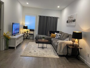 Uma sala de estar moderna com televisão, sofá, mesa de centro e luminárias.