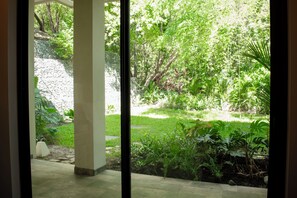 A view through a window of a garden with various plants and a stone wall. - Ocean and Mountain View Villa (Provincia de Guanacaste)