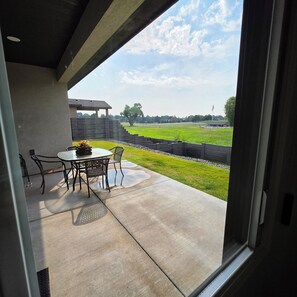 A patio with a table and chairs, a view of a grassy field, and a stone wall. - Pasco Luxury Retreat  4BR • Stunning Views • Fitness • AI Smart Home (Pasco)