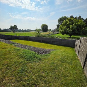 A grassy field with a stone wall and a tree. - Pasco Luxury Retreat  4BR • Stunning Views • Fitness • AI Smart Home (Pasco)