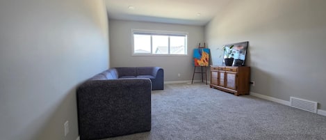A room with a dark-colored sofa, a blue couch, a wooden cabinet, and a painting on the wall.
