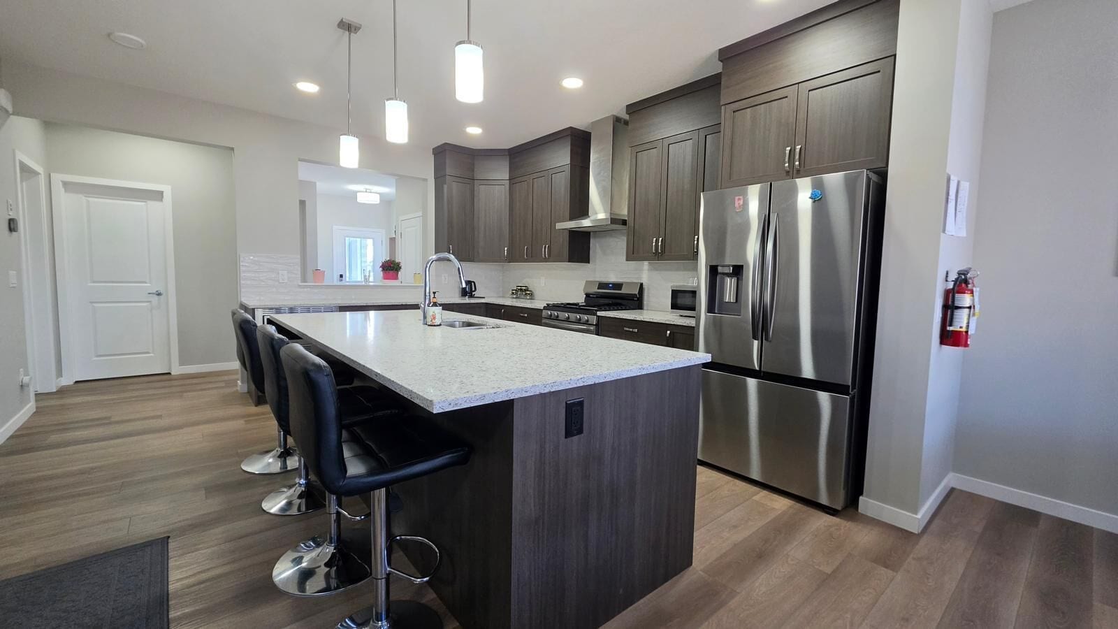 A modern kitchen with a central island, stainless steel appliances, and bar stools.