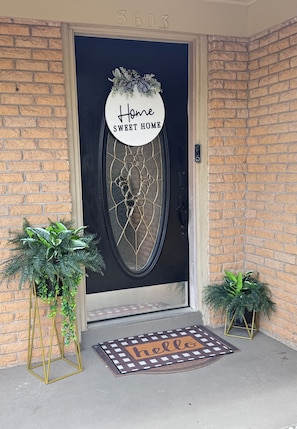 A front door with a decorative glass panel, a welcome mat, and two potted plants. - Maple Estate Private Pool, Hot Tub & Resort-Style Backyard (Odessa)