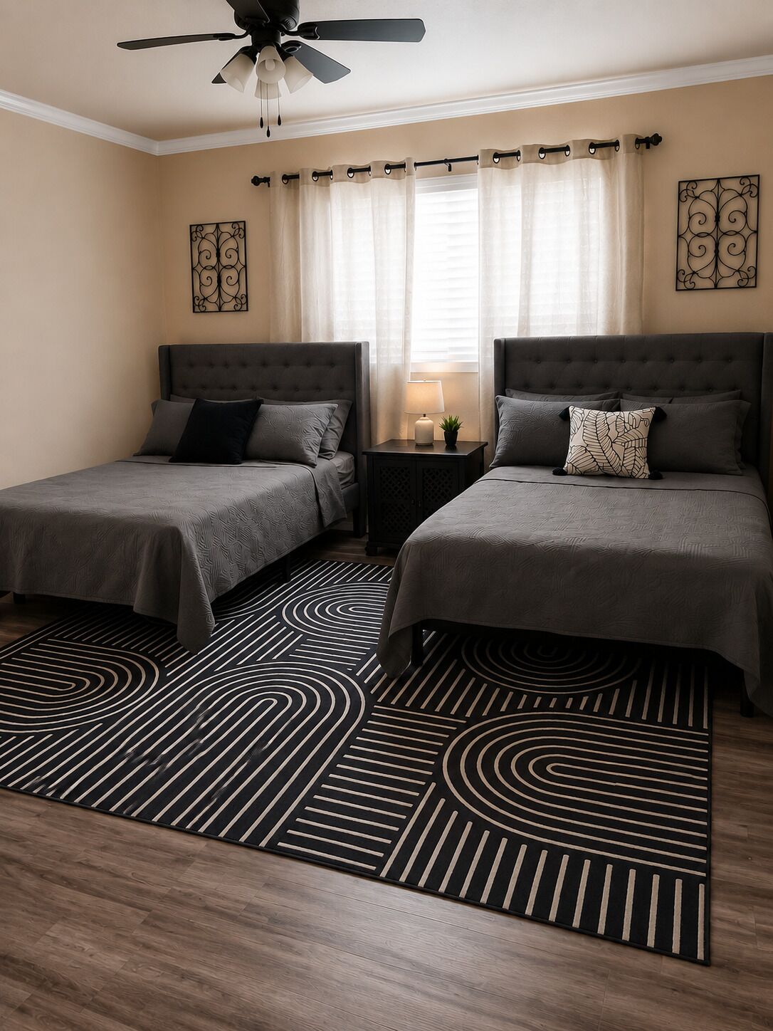Une chambre d’hôtel avec deux lits, un ventilateur de plafond, une fenêtre avec des rideaux et un tapis à motifs.