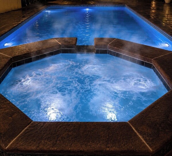 A hot tub with a geometric design, surrounded by dark tiles.