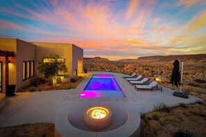 A modern outdoor pool area with a fire feature, lounge chairs, and a desert landscape in the background. - Sagebrush Hideaway Pool, Sauna, Cold Plunge, Views (Pioneertown)