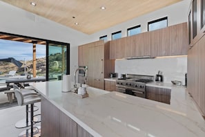 A modern kitchen with a large island, stainless steel appliances, and wooden cabinetry.