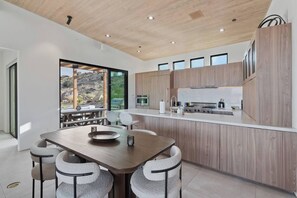 Une cuisine moderne avec des meubles en bois, un îlot central et un coin repas comprenant une table et des chaises.