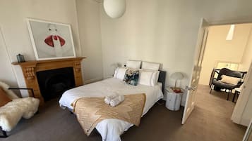 A bedroom with a bed, a fireplace, a door leading to another room, and a chair.