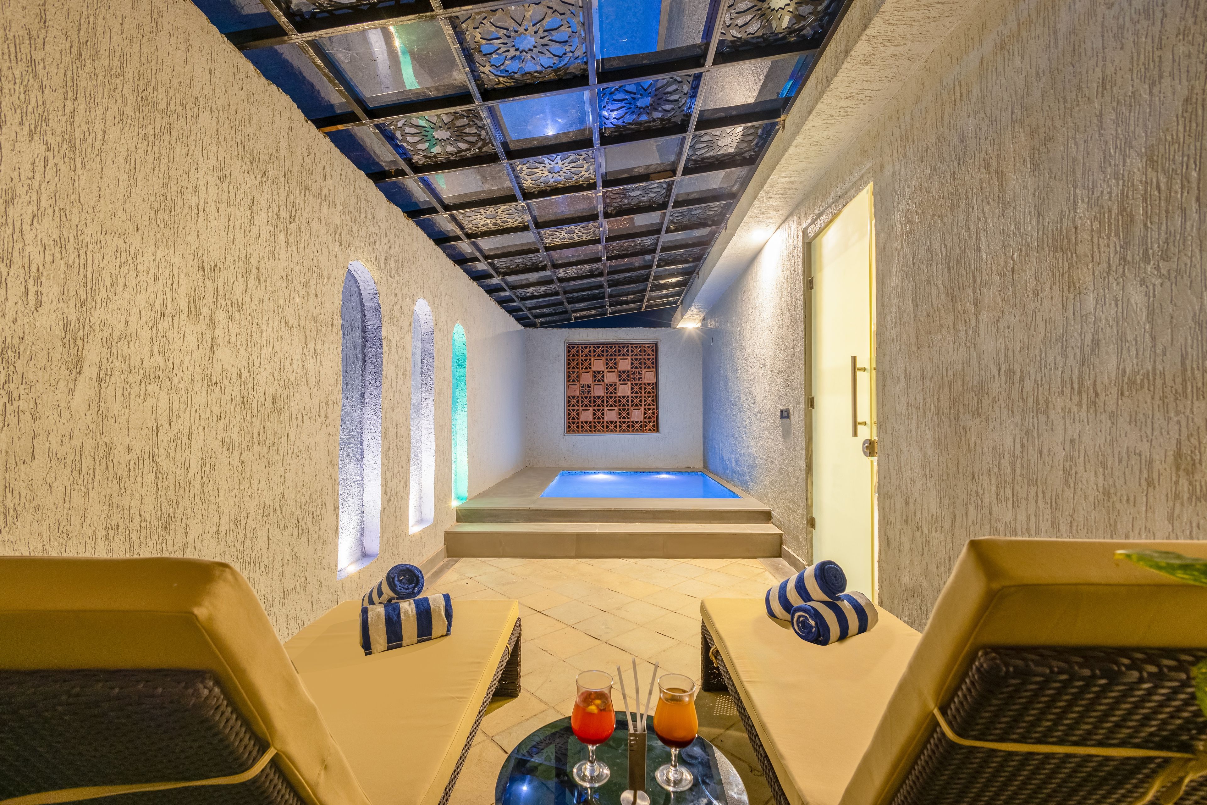 Un cuarto de spa con zona de relajación, una camilla de masaje y una pequeña piscina.