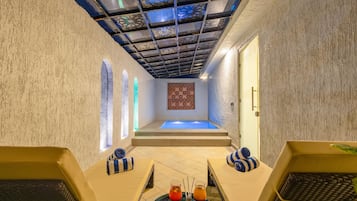 Un cuarto de spa con zona de relajación, una camilla de masaje y una pequeña piscina.