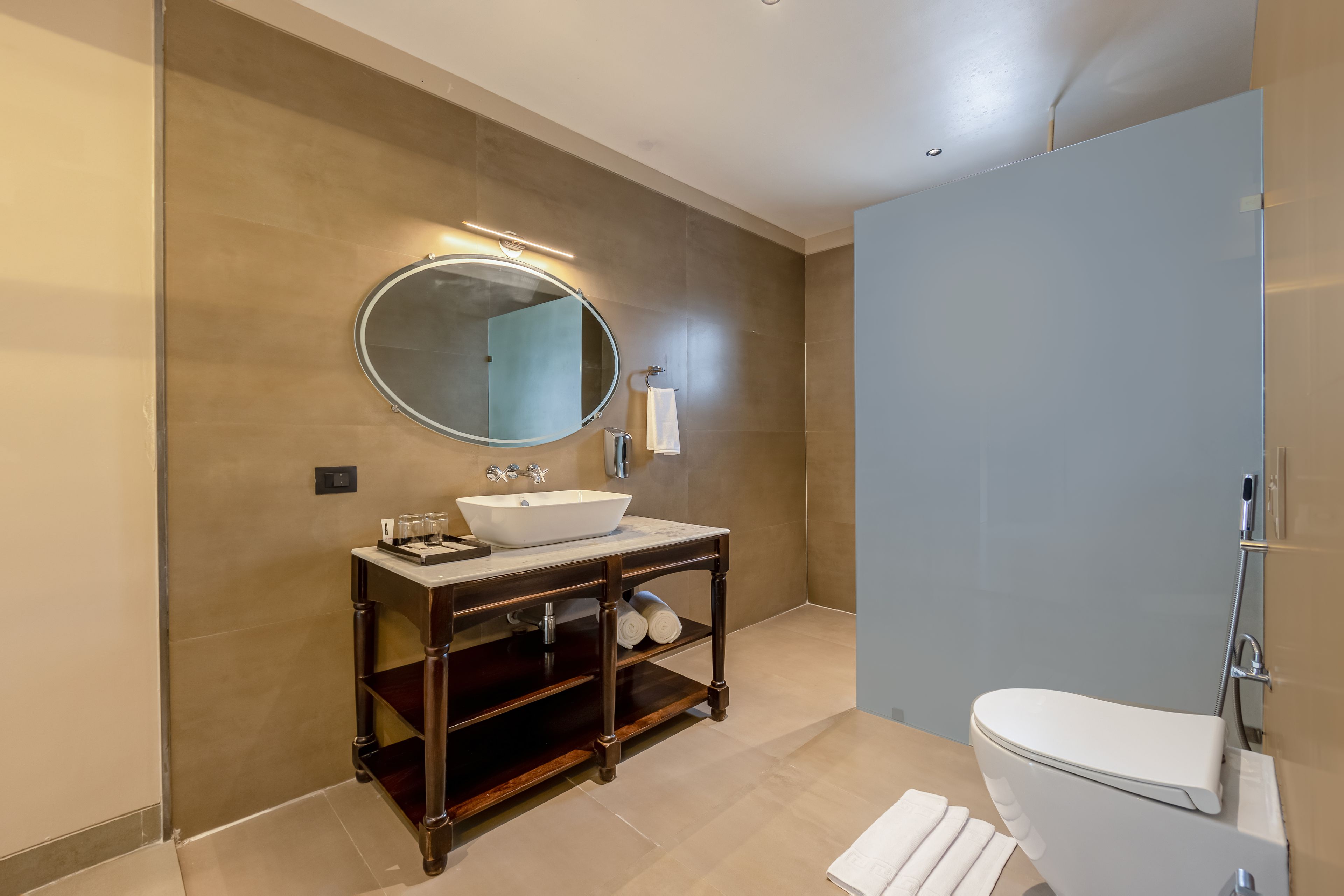 Un baño moderno con un espejo redondo, un lavamanos blanco y un inodoro.