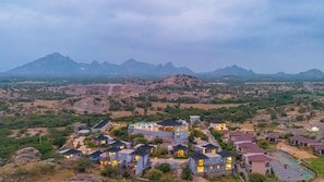 Un resort con varias construcciones, piscina y montañas al fondo.
