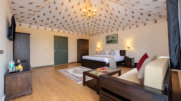 Una habitación de hotel con cama, sofá, mesa de centro, televisor y armario.