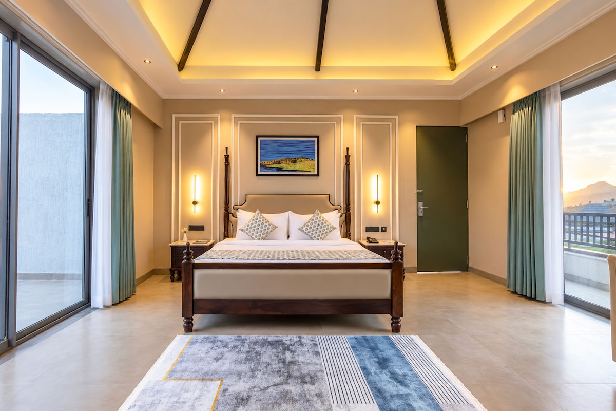 A spacious bedroom with a large bed, a view of the city, and a painting on the wall.