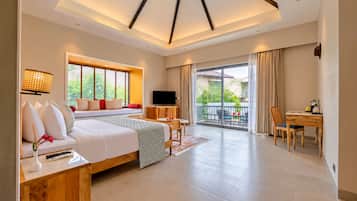 Una habitación de hotel moderna con una cama grande, televisión, balcón y zona de comedor.