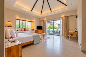 Una habitación de hotel moderna con una cama grande, televisión, balcón y zona de comedor.